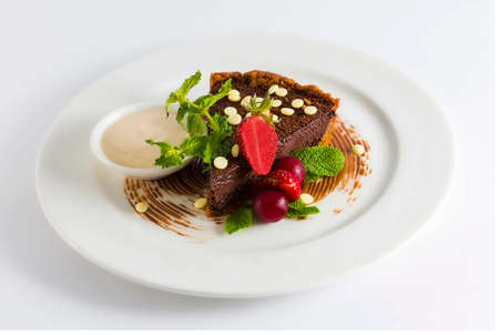Chocolate cake decorated with fruit and topped with herbs. Perfect for any party. Gourmet dessert.