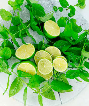 Ingredients for a refreshing Mojito cocktail: fresh lime fruit and mint leaves. Isolated on a white background. Top view.の写真素材