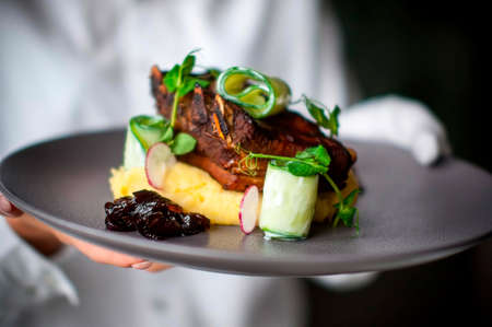 The chef serves grilled ribs with mashed potatoes with the addition of vegetables and plum jam to...