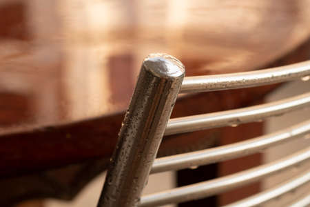 Rainy season. Stainless steel wet garden chair and mahogany table. Thailand.