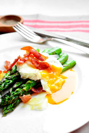 Green asparagus, topped with a poached egg and fried ham. Exquisite French cuisine. Gourmet meal.の写真素材