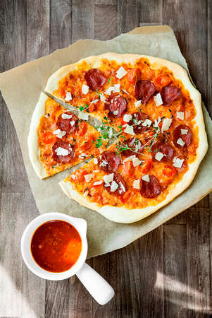 Slices of freshly baked Pepperoni pizza in a wood-fired oven. Pepperoni pizza is based on salami,...