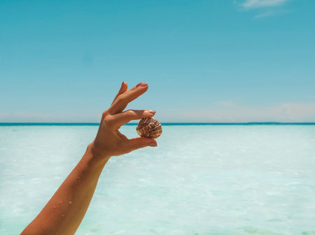 Female's hand showing tropical fauna,  scenery and sea in the background. Heaven on earth.の写真素材