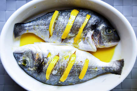 Preparation of sea bream (Dorada) carcass for baking. Stuffed with lemon slices.