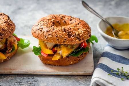 American bagel - sandwich with smoked fish, fried egg, avocado, sprinkled with rocket. Culinary and gastronomic concept. American cuisine.の写真素材
