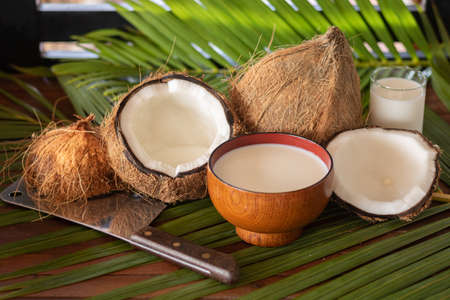 Composition depicting coconut, coconut cleaver machete, coconut halves after opening, coconut pulp...