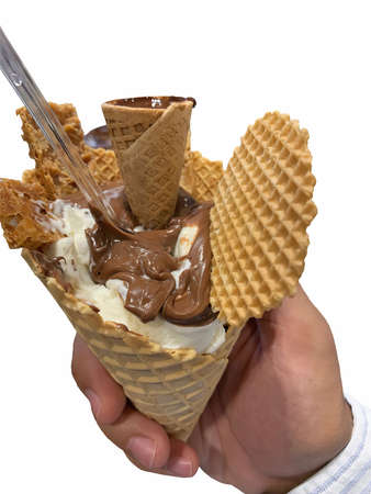 Italian chocolate and cream ice cream (gelato) decorated with a huge wafer held in the hand of a...