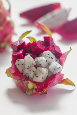 Diced red and white dragon fruit (pitaya) lying on the table. Ready-to-eat. Isolated on a white background. Close-up. Gourmet dessert. Culinary concept.の写真素材