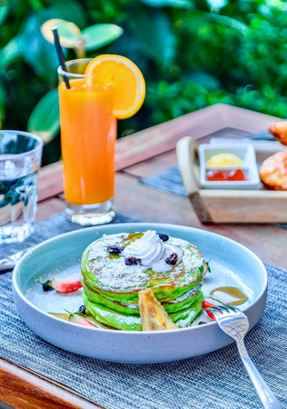 American pancakes with a hint of avocado decorated with whipped cream and raisins. Isolated on a light blue. Close-up. Macro. American cuisine. Perfect for breakfast or lunch.の写真素材