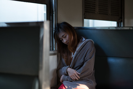Young woman looks sadly on the train