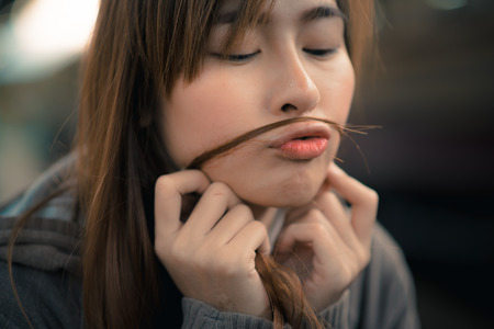 Young woman play with her hair and pucker up her lips