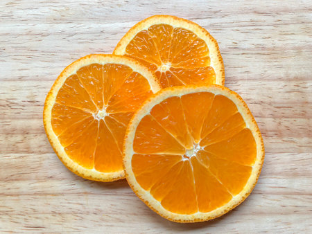 Sliced oranges arranged on a wooden board, bright orange, circular, rinded, as a background or wallpaper.の写真素材