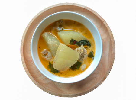 Winter melon curry with coconut milk and chicken in white cup on wooden plate, white background, top viewの写真素材