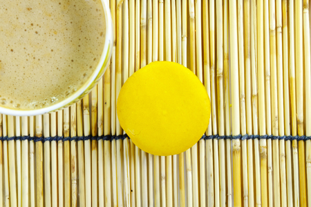 an orange flavor macaroon and a cup of coffee, on a traditional japanese style reeds matの写真素材