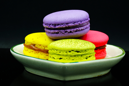 Assortment of colorful macaroons on a small green ceramic plateの写真素材