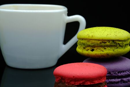 Assorted macaroons in vairous colors with a cup of coffee.の写真素材