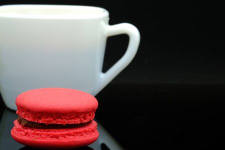 a raspberry flavor macaroon and a cup of coffeeの写真素材