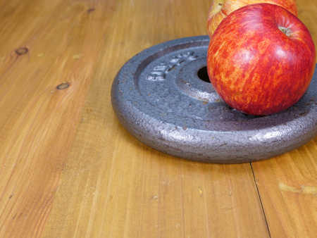 weight plates and red apple on a brown wood floorの写真素材