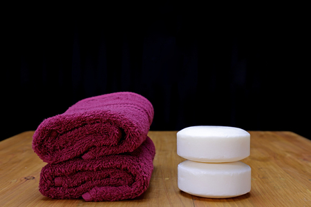 Red spa towels and white soap on wooden tableの写真素材