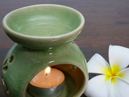 A green ceramic aromatherapy jar with a candle lit up in its chamber. Heated aromatherapy oil mixed with water produces a pleasant and soothing smell.の写真素材