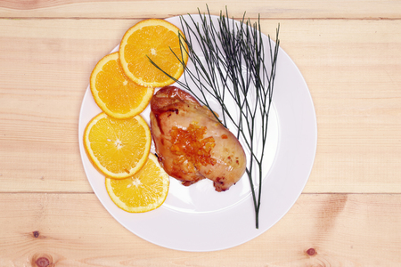 roasted chicken with navel orange and marmalade on a natural wood plank backgroundの写真素材