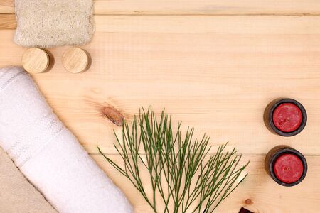 white and light brown towels, red candles, and bottles  of aromatic skin care products on a wooden backgroundの写真素材