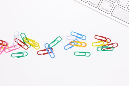 colorful paper clips on an office desk with a white keyboardの写真素材