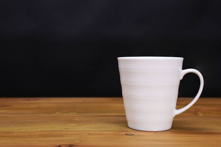 a white porcelain coffee mug on a brown wooden tableの写真素材