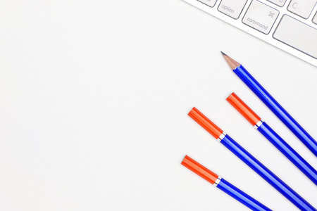 high angle view of a clean office space with pencils and a computer keyboard on white backgroundの写真素材