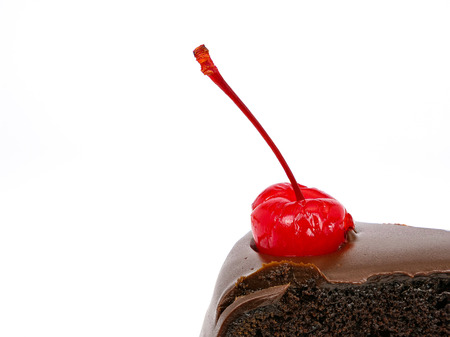 Side view shot of a slice of chocolate cake with cherries and cream filling and chocolate fudge (black forest cake) , isolated on white backgroundの写真素材