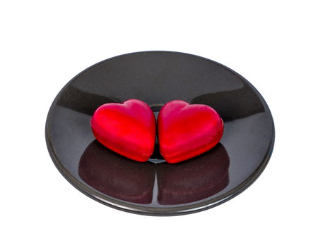 two heart shape chocolate candies on a black ceramic plate, isolated on white background, valentine's day conceptの写真素材