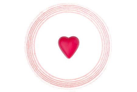a heart made from dark chocolate coated with red color on a round white ceramic plate, isolated on white backgroundの写真素材