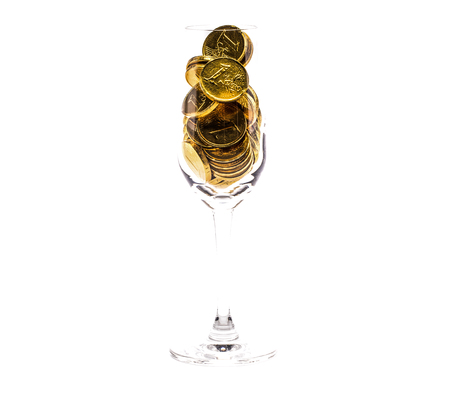 a heap of gold coins in a tall glass, isolated on white backgroundの写真素材