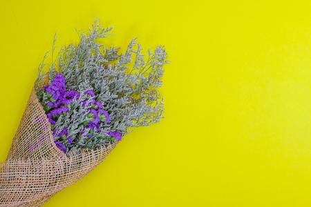 a bouquet of dried purple statice on bright yellow background, top view, card, love, romance, wedding invitation conceptの写真素材