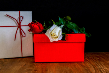 two beautiful roses and two boxes on a brown wooden table の写真素材