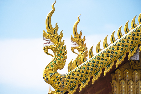Wood gables sculptured as mythical golden serpent-like being are seen decorating roof top of Wat Phra Thad Hariphunchai temple in Lumpoon Province, Thailandの写真素材