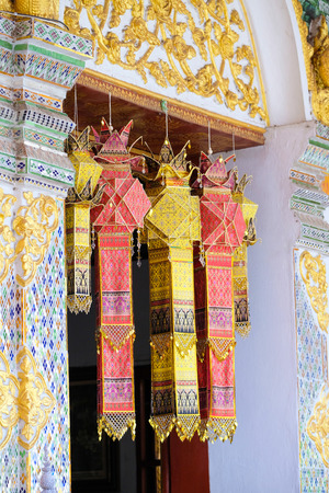 a group of colorful traditional hand painted silk cloth lanterns decorating the window of the main temple of Wat Phra That Hariphunchai, the iconic Buddhist landmark in Lamphun City, Thailandの写真素材