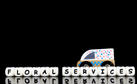 Alphabet letters spelling words floral services with a wooden model transpotation in the background....