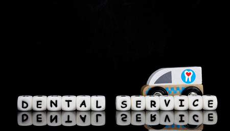 Alphabet letters spelling a word dental service with a model ambulance in the background. Ambulatory dental service concept.の写真素材