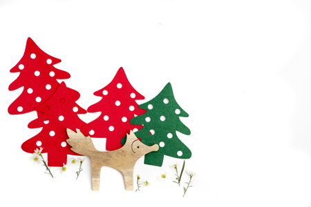 A little wooden fox with tiny white flowers and green and red pine trees background. Holidays concept.の写真素材