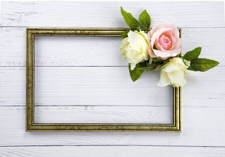 Gold colored vintage wooden frame decorated  with  beutiful  pink and white roses.  Template mock up. Copy space for text.  White background.の写真素材
