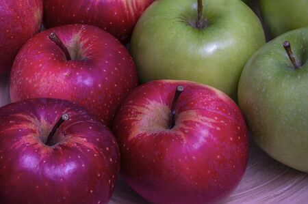 Closeup of red and green apples on a bamboo plate.