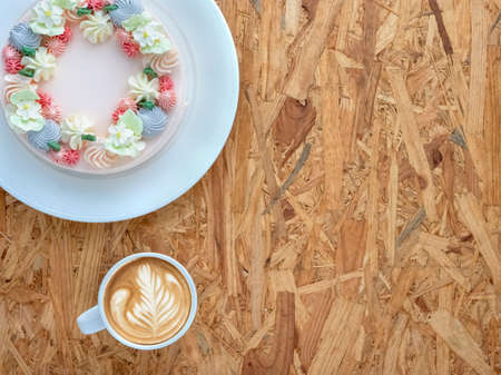 Beautifully decorated cake with cup of coffee on rustic wooden board background. top view, flat lay,...