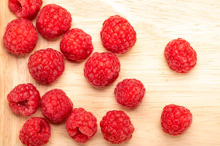 Fresh ripe raspberries on a wooden plate.