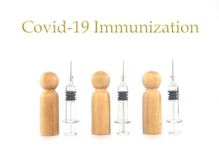 Wooden man models and clean glass syringes in a row. Covid-19 vaccination concept.の写真素材