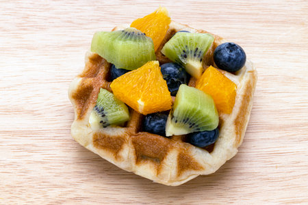 A piece of morning waffle and mixed fruits on a wooden board.
