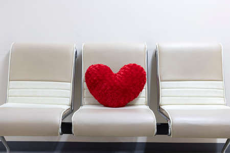A red heart shaped velvet pillow left on a leather chair in the waiting room lounge. Social...
