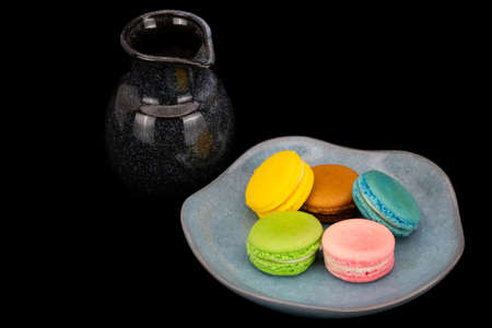 Colorful macaroons on blue ceramic plate with a dark blue ceramic jar.の写真素材
