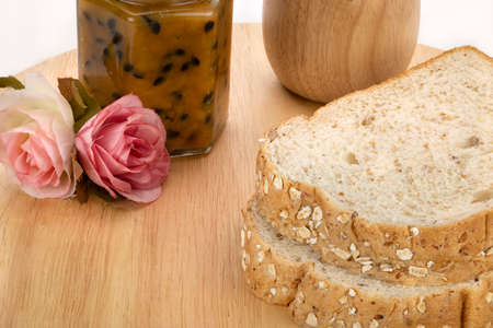 Slices of bread with passion fruit jam on a wooden plate.の写真素材