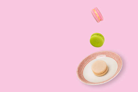 Colorful macaroons floating on a ceramic plate. Beautiful soft pink background. Leviatation food concept.の写真素材